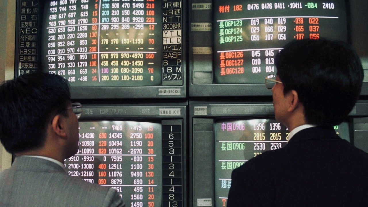 Two Japanese businessmen looking at stock market data in the 1980's.